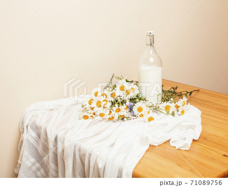 Simply stylish wooden kitchen with bottle of milk and glass on table, summer flowers camomile, healthy foog moring concept Simply stylish wooden kitchen with bottle of milk and glass on table, summer flowers camomile, healthy foog moring concept 71089756