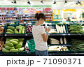 Woman using mobile phone while shopping in supermarket 71090371