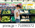 Young woman with face mask using mobile phone and buying groceries in the supermarket 71090372