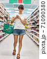 Woman in supermarket checking shopping list on smartphone 71090380