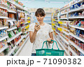 Woman using mobile phone while shopping in supermarket 71090382
