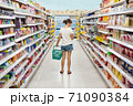 Woman shopping in a supermarket looking at the screen of the phone her shopping list 71090384