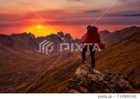 Woman Standing on Rocks looking at Scenic Mountain Peaks and Valley 71090540