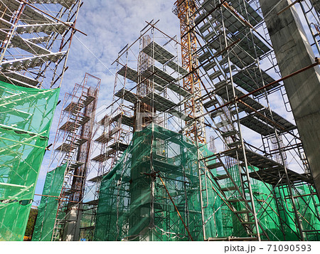 SHAH ALAM, MALAYSIA -AUGUST 6, 2020: Temporary staircase and scaffolding are used in the construction of high concrete columns. Scaffolding is wrapped with safety netting for safety purposes. Installe SHAH ALAM, MALAYSIA -AUGUST 6, 2020: Temporary staircase and scaffolding are used in the construction of high concrete columns. Scaffolding is wrapped with safety netting for safety purposes. Installe 71090593