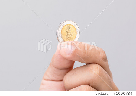 Hand holding Thailand coin (10 baht). Studio shot on grey background Hand holding Thailand coin (10 baht). Studio shot on grey background 71090734