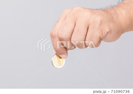 Hand holding Thailand coin (10 baht). Studio shot on grey background Hand holding Thailand coin (10 baht). Studio shot on grey background 71090736