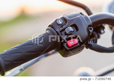 Red horn switch. Left handle bar with hand clutch of motorcycle. Motorcycle maintenance concept outdoor shooting with sunset effect Red horn switch. Left handle bar with hand clutch of motorcycle. Motorcycle maintenance concept outdoor shooting with sunset effect 71090746