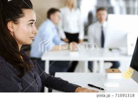 Business woman using computer at workplace in modern office. Brunette secretary or female lawyer looking at the camera and happy smiling. Working for pleasure and success Business woman using computer at workplace in modern office. Brunette secretary or female lawyer looking at the camera and happy smiling. Working for pleasure and success 71091318