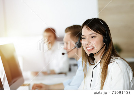 Asian woman working at customer service office. Business concept. Group of diverse operators at work in sunny call center. Asian woman working at customer service office. Business concept. Group of diverse operators at work in sunny call center. 71091453
