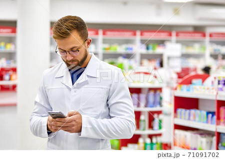handsome pharmacist man using smartphone at work 71091702