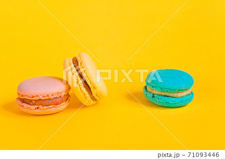 Sweet almond colorful unicorn pink blue yellow green macaron or macaroon dessert cake isolated on trendy yellow modern fashion background. French sweet cookie. Minimal food bakery concept Copy space Sweet almond colorful unicorn pink blue yellow green macaron or macaroon dessert cake isolated on trendy yellow modern fashion background. French sweet cookie. Minimal food bakery concept Copy space 71093446