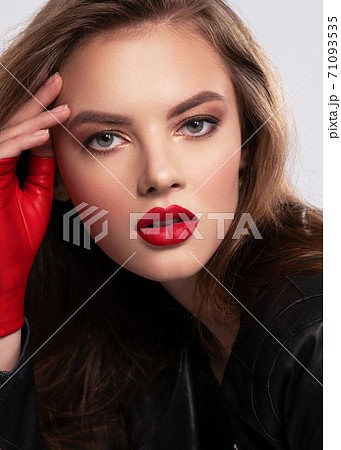 Portrait of beautiful young woman with bright makeup. Beautiful brunette with bright red lipstick on her lips. Pretty girl with long brown hair. Brunette dressed in a black leather jacket. Sexy girl Portrait of beautiful young woman with bright makeup. Beautiful brunette with bright red lipstick on her lips. Pretty girl with long brown hair. Brunette dressed in a black leather jacket. Sexy girl 71093535