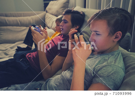 Three boys spending time in a social network using mobile phones.  Children with smartphones at home. White kids using cell phones for gaming. People and social media concept 71093996