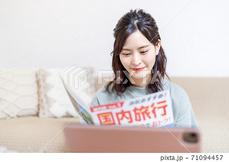 パンフを見ながらパソコンで旅行計画を立てる若い女性 パンフを見ながらパソコンで旅行計画を立てる若い女性 71094457