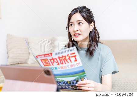パンフを見ながらパソコンで旅行計画を立てる若い女性 パンフを見ながらパソコンで旅行計画を立てる若い女性 71094504