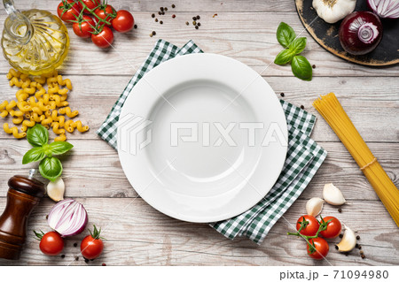 Food cooking background with vegetables, pasta and empty white plate Food cooking background with vegetables, pasta and empty white plate 71094980