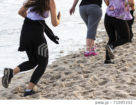 Looking down at a few people running and walking on the beach by the water Looking down at a few people running and walking on the beach by the water 71095332