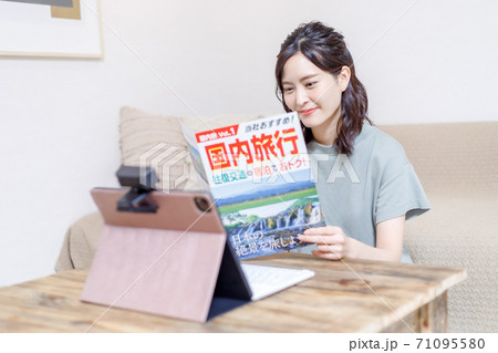 パンフを見ながらパソコンで旅行計画を立てる若い女性 パンフを見ながらパソコンで旅行計画を立てる若い女性 71095580