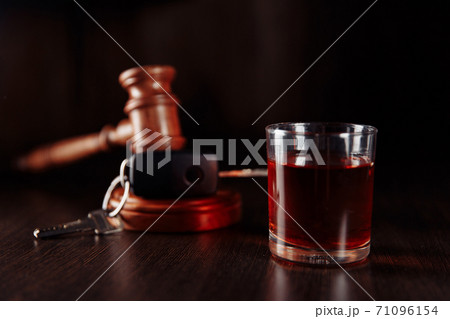 Car key, wooden judge gavel and bottle of alcohol with glass close-up. Drink driving concept 71096154