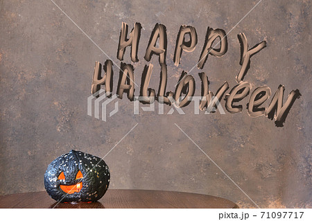black colored pumpkin with glitter on wooden stool in front of a brown backdrop 71097717