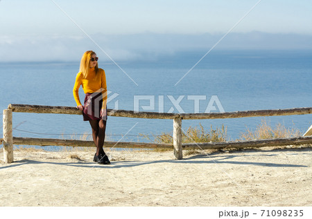 The girl sat down on a fence made of a wooden frame against the background of the sea 71098235