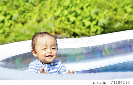 真夏の暑い日に 外でプールで水遊びしている子供 かわいい笑顔の子供の写真素材