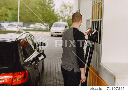 Handsome man pours gasoline into tank of car Handsome man pours gasoline into tank of car 71107845