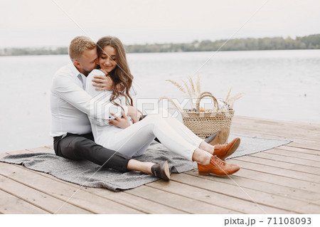 People sitting by the water with picnic set 71108093