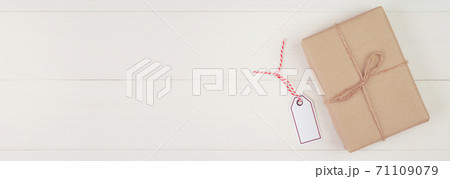 Gift box with kraft paper and tag or label on wooden table in Christmas day or holiday. 71109079