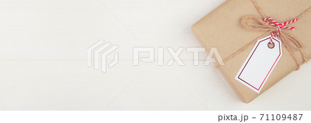 Gift box with kraft paper and tag or label on wooden table in Christmas day or holiday. 71109487