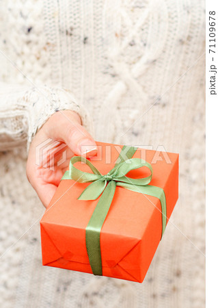Woman holding a gift box tied with green ribbon in the hand. 71109678