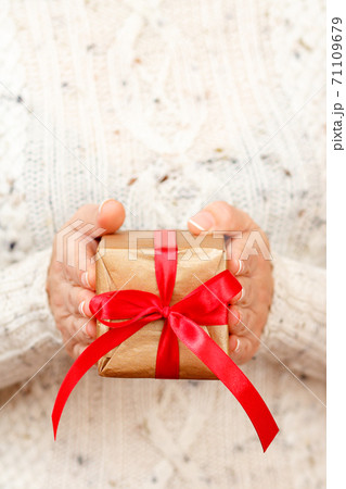 Woman holding a gift box tied with red ribbon in the hands. 71109679