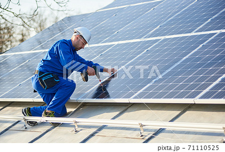 Electrician mounting solar panel on roof of modern house 71110525