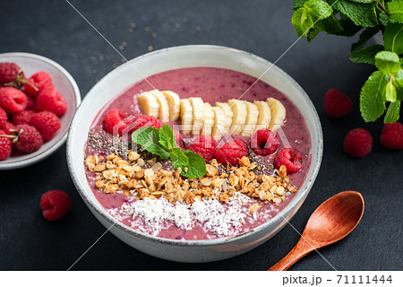 Pink smoothie bowl with raspberry, banana, granola and coconut 71111444
