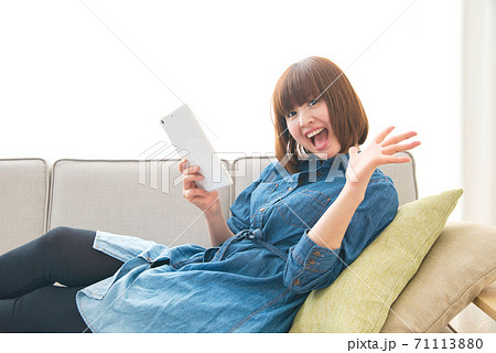 お家時間をソファでくつろぎながらタブレットを使う若い女性 お家時間をソファでくつろぎながらタブレットを使う若い女性 71113880