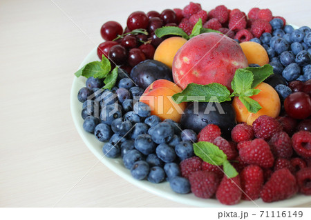 Summer mix of berries on a white plate .Texture or background Summer mix of berries on a white plate .Texture or background 71116149