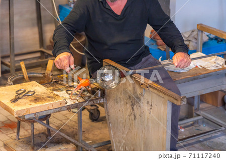 Artisan making handmade glassware in high temperature flame in Italy  71117240