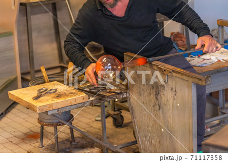 Glass blowing artisan making product under high temperature flame Glass blowing artisan making product under high temperature flame 71117358