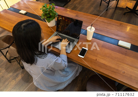 Woman freelancer typing laptop computer next to cellphone Woman freelancer typing laptop computer next to cellphone 71117632