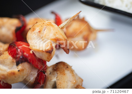 Traditional, oriental and Asian kebabs on a wooden skewer of grilled chicken pieces boiled rice as a garnish. 71120467
