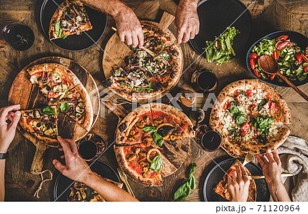 People eating various kinds of pizza and drinking People eating various kinds of pizza and drinking 71120964