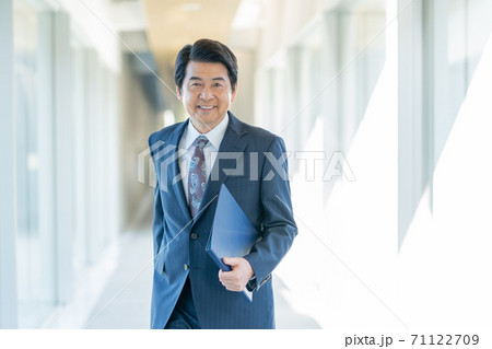 オフィスの通路を前進するシニア男性 71122709