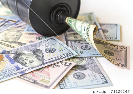 Barrel of oil on a background, american dollars background. Falling trend of barrel price decrease of earning and global economics . Selective focus. 71126247