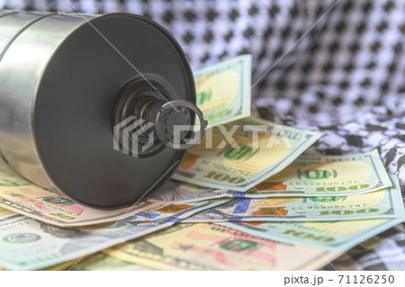 Barrel of oil on a background, american dollars and arabian background. Falling trend of barrel price decrease of earning and global economics . Selective focus. 71126250