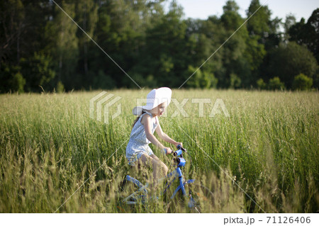 6 year old girl riding a bicycle of a grass covered field. 6 year old girl riding a bicycle of a grass covered field. 71126406