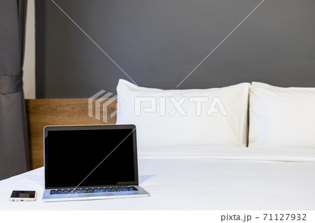 Laptop computer with blank screen with smart phone on white bed decoration in hotel bedroom interior background,Work and business in leisure with travel in the holiday concept. 71127932