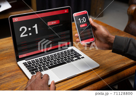 Close up laptop and smartphone screen with mobile app for betting and score 71128800