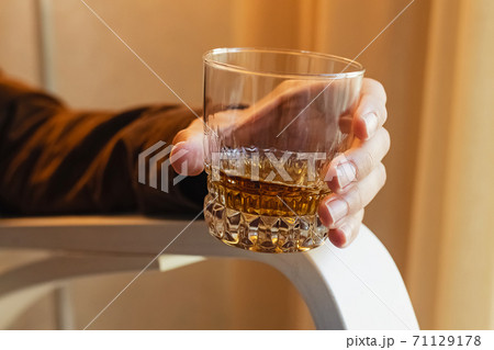 Man sitting on the chair and drinking whiskey. 71129178