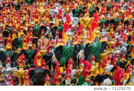 Chicken statues of various colors and sizes that people worship in the mystery of their beliefs. 71129270
