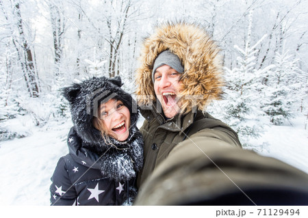Season and relationship concept - Funny couple taking selfie in the winter time 71129494